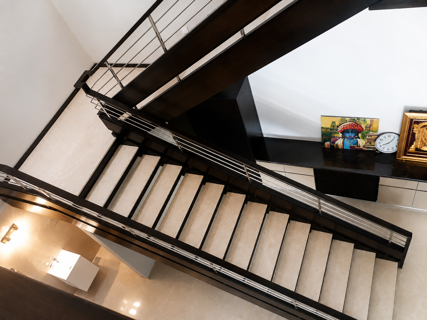 Dual flight staircase with dark wood and steel balustrade by Lotey Metalcrafts